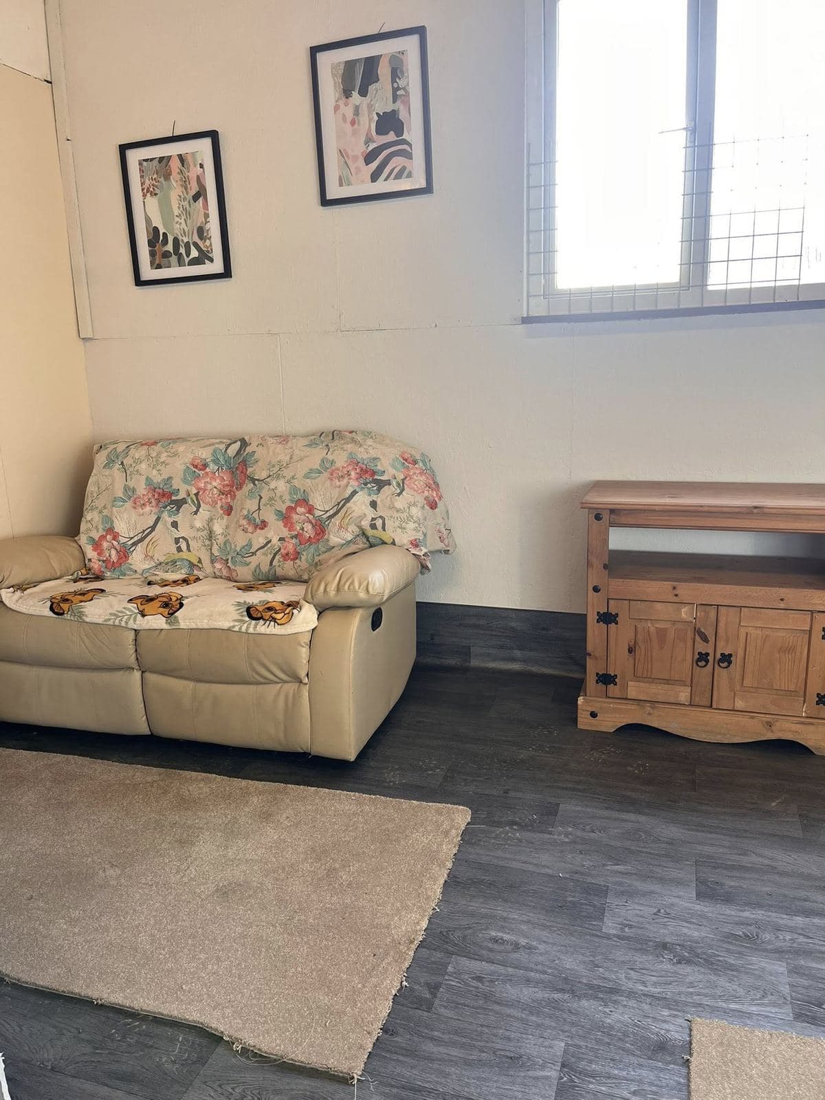 Tresmeer sofa room — cream leather recliner with floral throw, pine TV cabinet, framed botanical prints